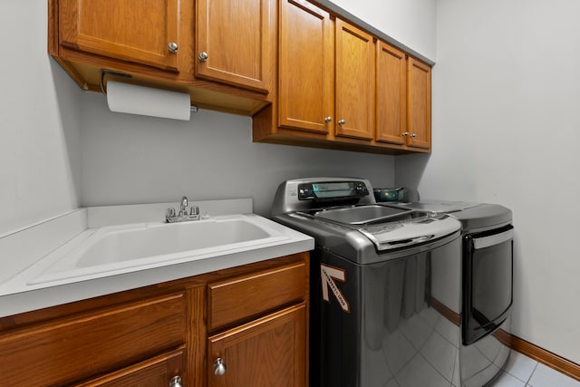 laundry area with cabinet space, washing machine and dryer, baseboards, and a sink