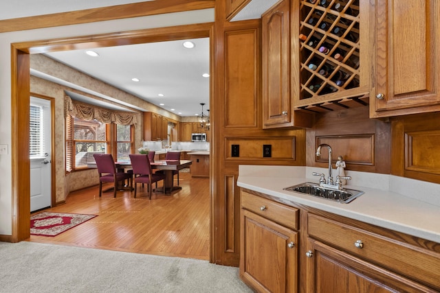 kitchen featuring brown cabinetry, stainless steel microwave, light countertops, and a sink