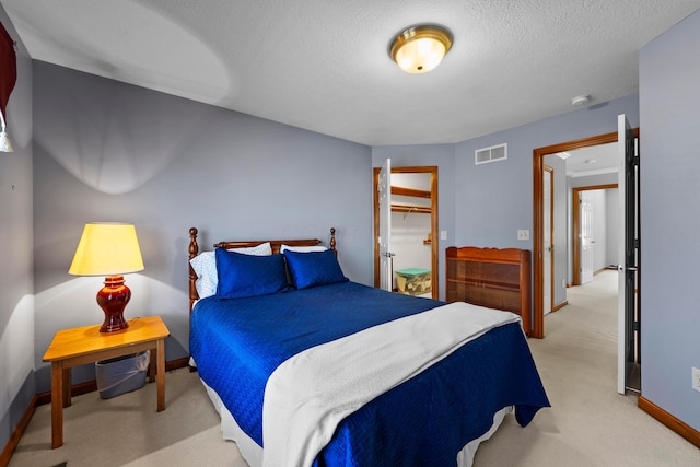 bedroom with baseboards, visible vents, a closet, a textured ceiling, and light colored carpet