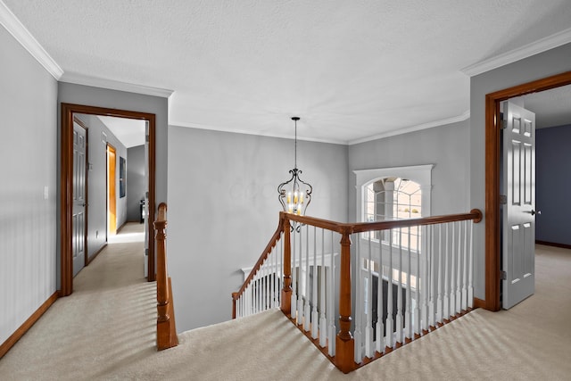 corridor with an upstairs landing, carpet floors, ornamental molding, and an inviting chandelier