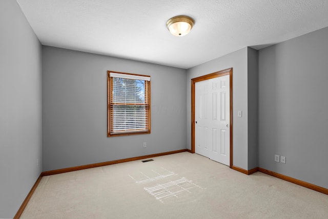 unfurnished bedroom featuring visible vents, baseboards, a textured ceiling, and carpet flooring