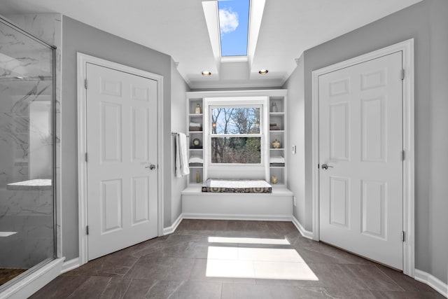 interior space featuring crown molding, a skylight, and baseboards