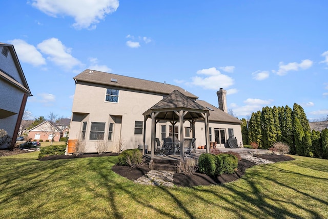 back of house with a gazebo, stucco siding, a chimney, a yard, and a patio