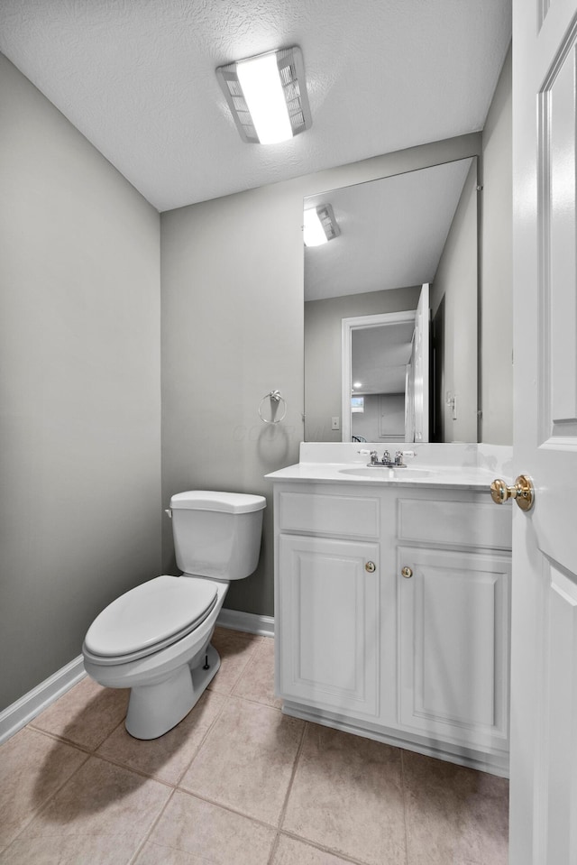 bathroom featuring baseboards, toilet, vanity, tile patterned floors, and a textured ceiling