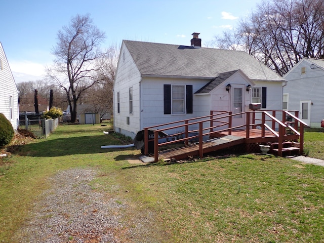 view of front of house with a deck, a front lawn, fence, roof with shingles, and a chimney