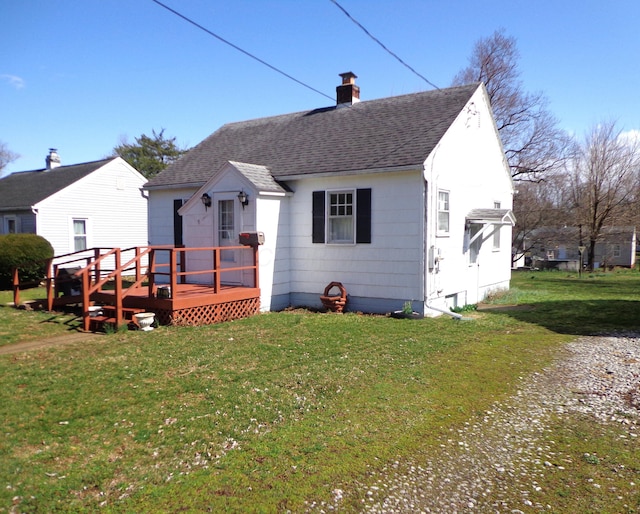 rear view of house featuring a yard, a deck, a chimney, and roof with shingles