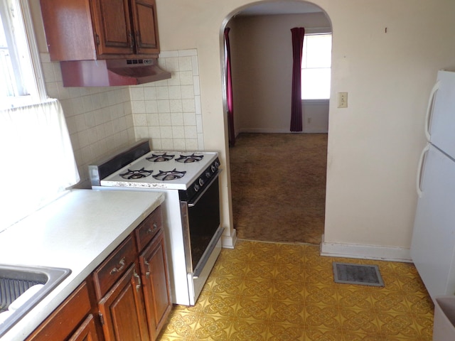 kitchen featuring white appliances, visible vents, arched walkways, light countertops, and tasteful backsplash