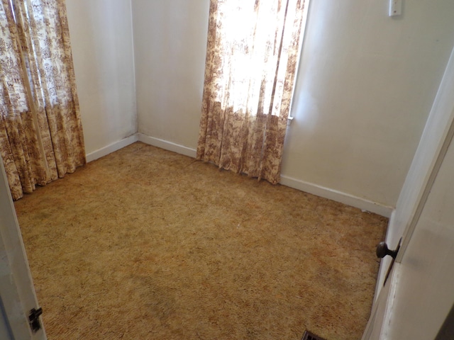 carpeted empty room featuring baseboards