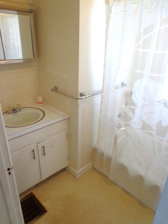 bathroom with visible vents, vanity, tile walls, and a wainscoted wall