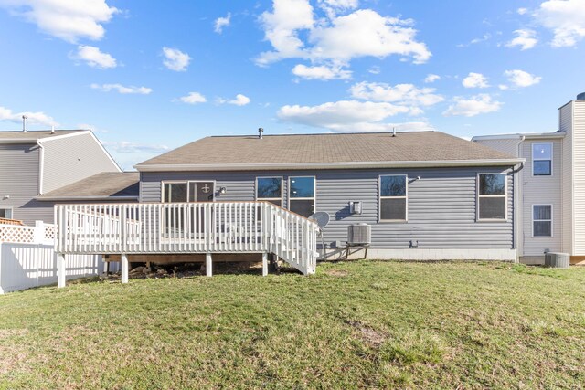 rear view of house featuring central AC unit, fence, a shingled roof, a deck, and a lawn