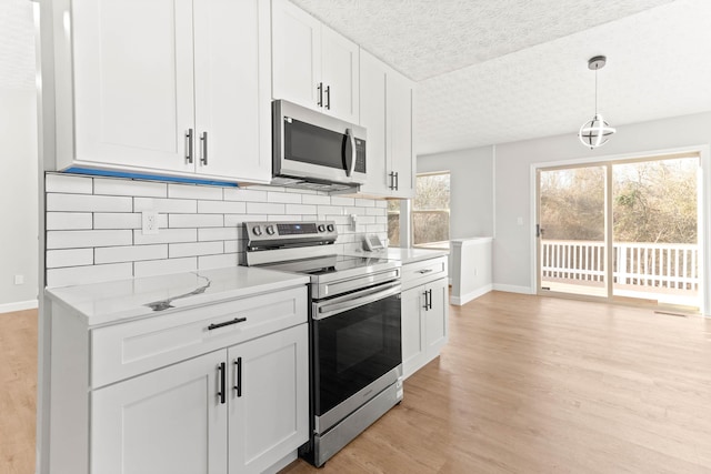 kitchen featuring a textured ceiling, tasteful backsplash, white cabinetry, stainless steel appliances, and light wood finished floors