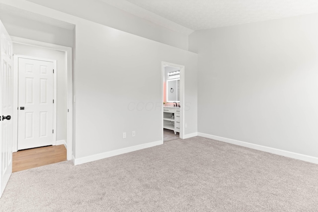 unfurnished bedroom featuring baseboards, carpet floors, and ensuite bathroom