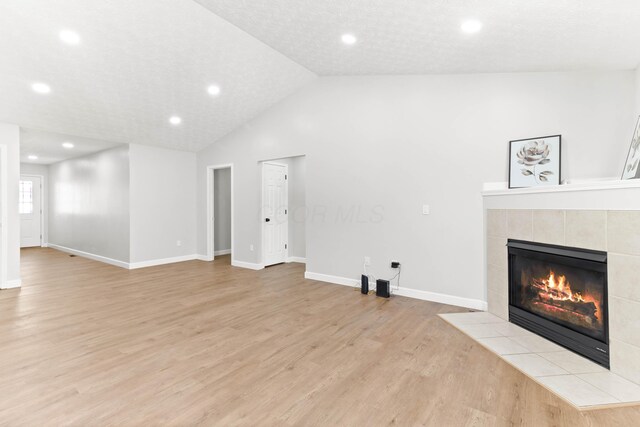unfurnished living room with baseboards, light wood finished floors, lofted ceiling, recessed lighting, and a fireplace