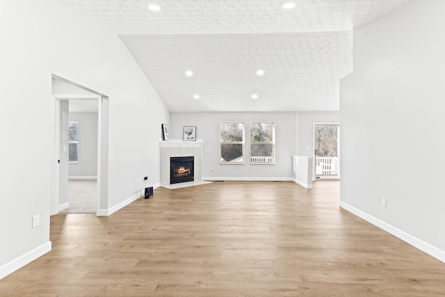 unfurnished living room featuring light wood-style flooring, baseboards, and a textured ceiling