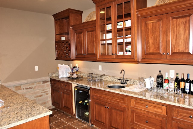6884 Ballantrae Pl, Dublin, OH 43016 - kitchen with a sink, light stone counters, wine cooler, brown cabinetry, and glass insert cabinets