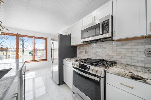 kitchen featuring light stone counters, stainless steel appliances, decorative backsplash, white cabinets, and a textured ceiling