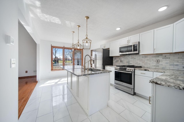 kitchen featuring backsplash, white cabinetry, stainless steel appliances, and light stone countertops