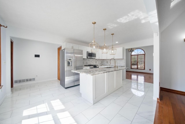 kitchen featuring visible vents, a sink, decorative backsplash, stainless steel appliances, and white cabinetry