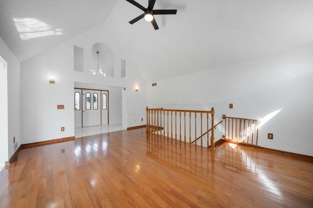 interior space featuring hardwood / wood-style floors, baseboards, high vaulted ceiling, and ceiling fan