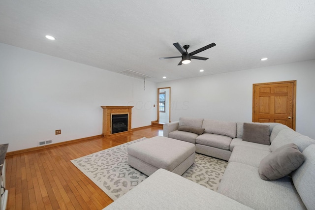 living area featuring a ceiling fan, baseboards, visible vents, attic access, and light wood-type flooring