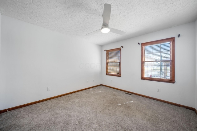 unfurnished room with a ceiling fan, visible vents, baseboards, a textured ceiling, and carpet flooring