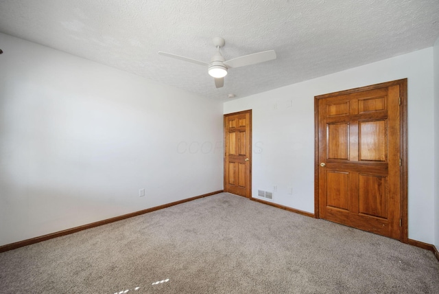 unfurnished bedroom featuring visible vents, a textured ceiling, baseboards, and carpet