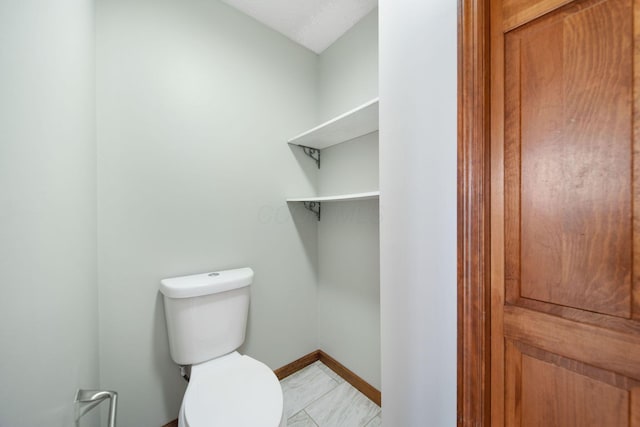 bathroom with toilet and baseboards