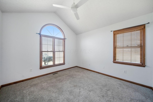 unfurnished room featuring a ceiling fan, visible vents, lofted ceiling, a textured ceiling, and carpet flooring