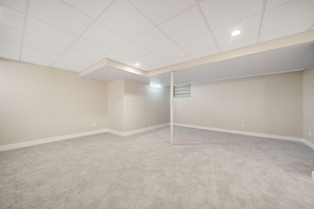 finished basement featuring carpet, baseboards, and a drop ceiling