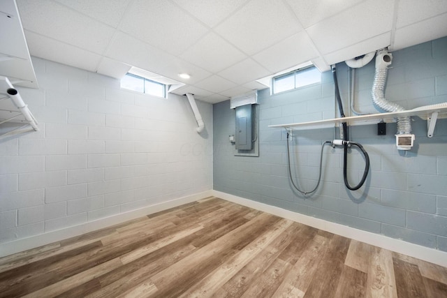 basement with electric panel, concrete block wall, wood finished floors, and plenty of natural light