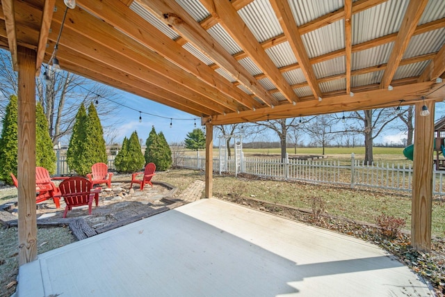 view of patio with a rural view, fence, and a fire pit