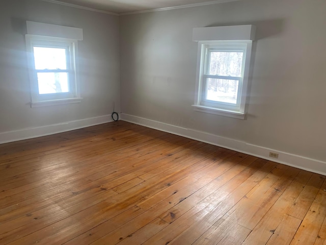 spare room featuring crown molding, light wood-style floors, and baseboards