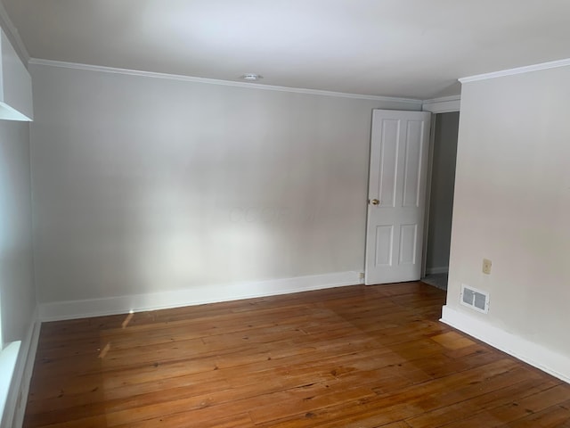 spare room with visible vents, ornamental molding, baseboards, and wood-type flooring