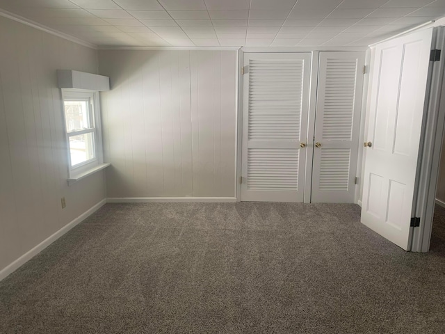 unfurnished bedroom featuring a closet, carpet floors, baseboards, and ornamental molding