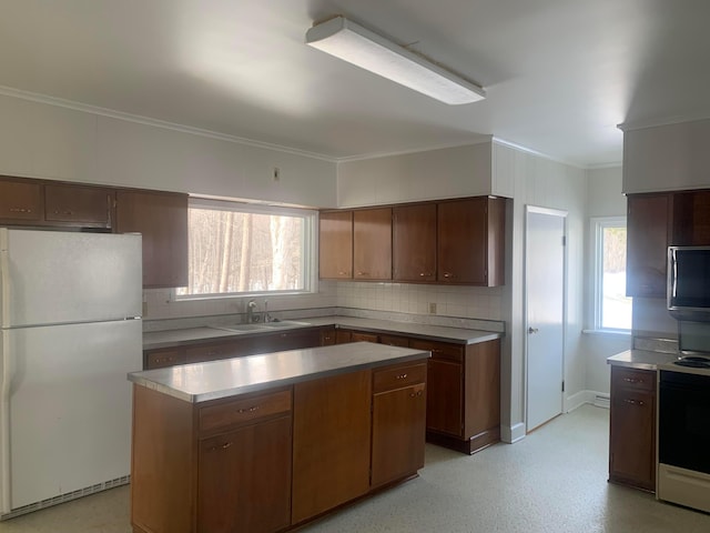 kitchen with a sink, tasteful backsplash, a kitchen island, freestanding refrigerator, and light countertops