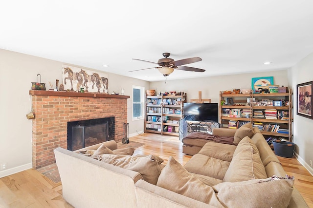 living room featuring light wood-style flooring, recessed lighting, a fireplace, baseboards, and ceiling fan