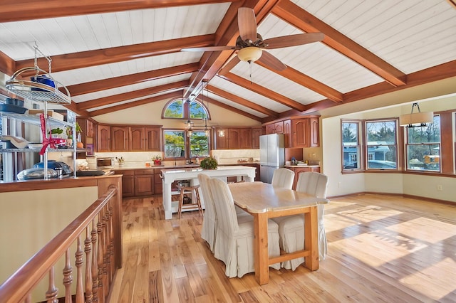 dining space with light wood-style flooring, baseboards, lofted ceiling with beams, and ceiling fan