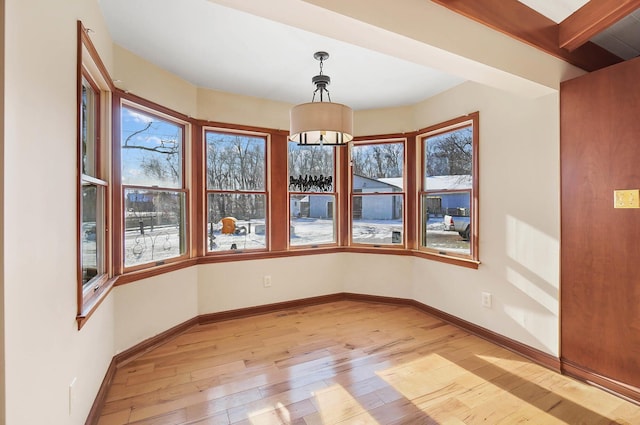 unfurnished dining area featuring baseboards, a chandelier, and light wood finished floors