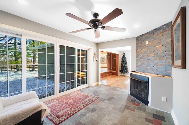 sitting room featuring baseboards, recessed lighting, a fireplace, stone finish floor, and a ceiling fan