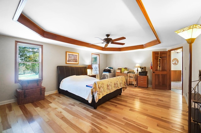 bedroom with a tray ceiling, baseboards, a ceiling fan, and light wood finished floors