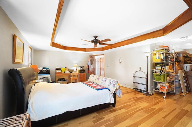 bedroom with a tray ceiling, baseboards, light wood-style flooring, and a ceiling fan