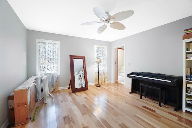 interior space with stairway, light wood-style floors, baseboards, and ceiling fan