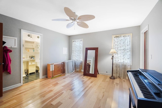 bedroom with light wood-style flooring, baseboards, and ceiling fan