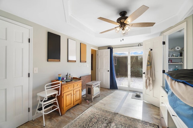 interior space with a raised ceiling, a wood stove, and ceiling fan