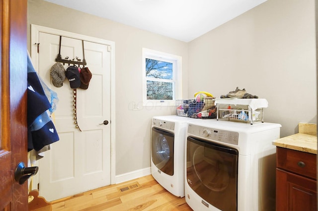 washroom featuring visible vents, washer and clothes dryer, light wood-style floors, baseboards, and laundry area