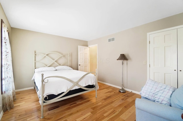 bedroom with light wood finished floors, visible vents, and baseboards