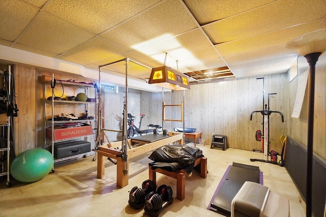 exercise area with a paneled ceiling and wood walls