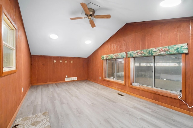 bonus room featuring lofted ceiling, wooden walls, a ceiling fan, and light wood finished floors