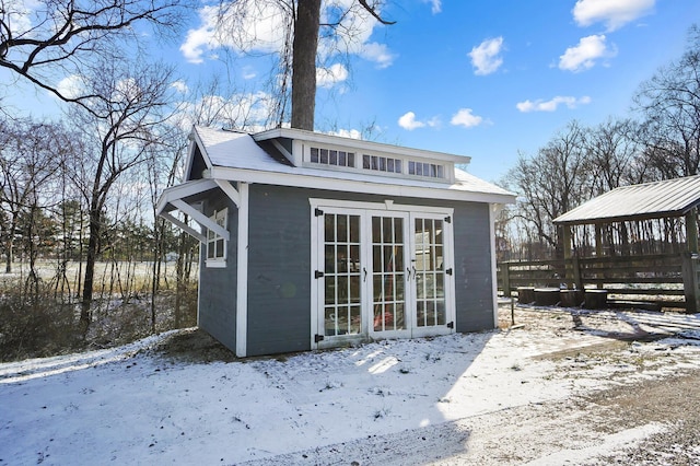 snow covered structure featuring an outbuilding and french doors