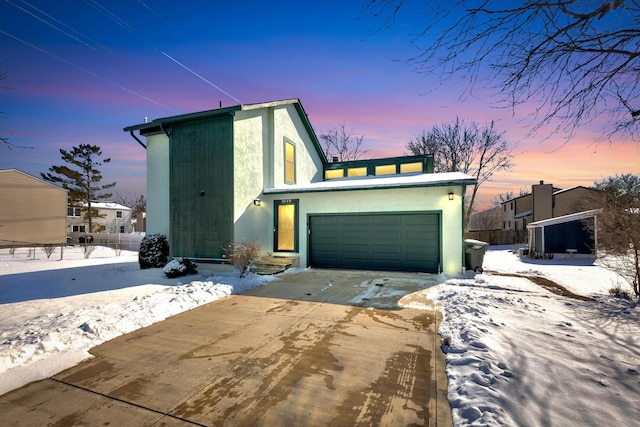 view of front of home with stucco siding, driveway, and fence